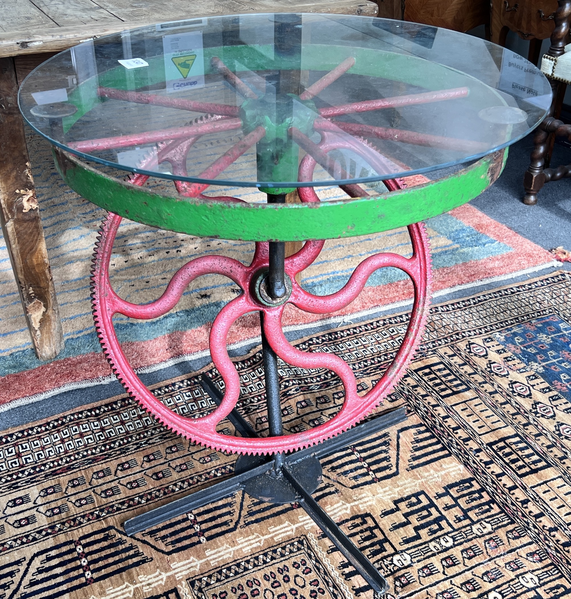 A wrought iron and glass occasional table constructed from cogs and wheels, diameter 70cm